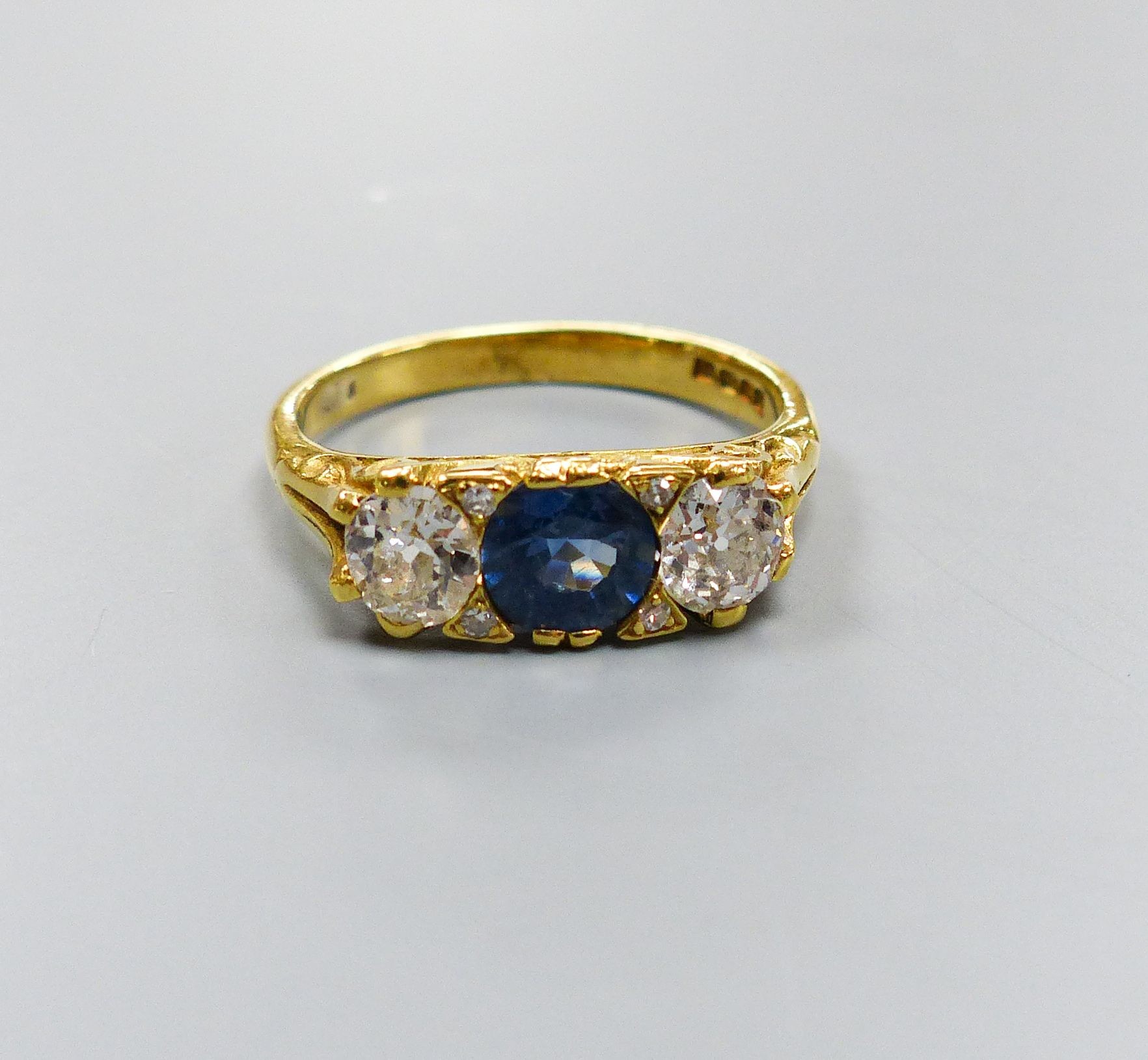 A 1970's Victorian style 18ct gold, single stone synthetic? sapphire and two stone diamond set ring, size N, gross weight 4.3 grams